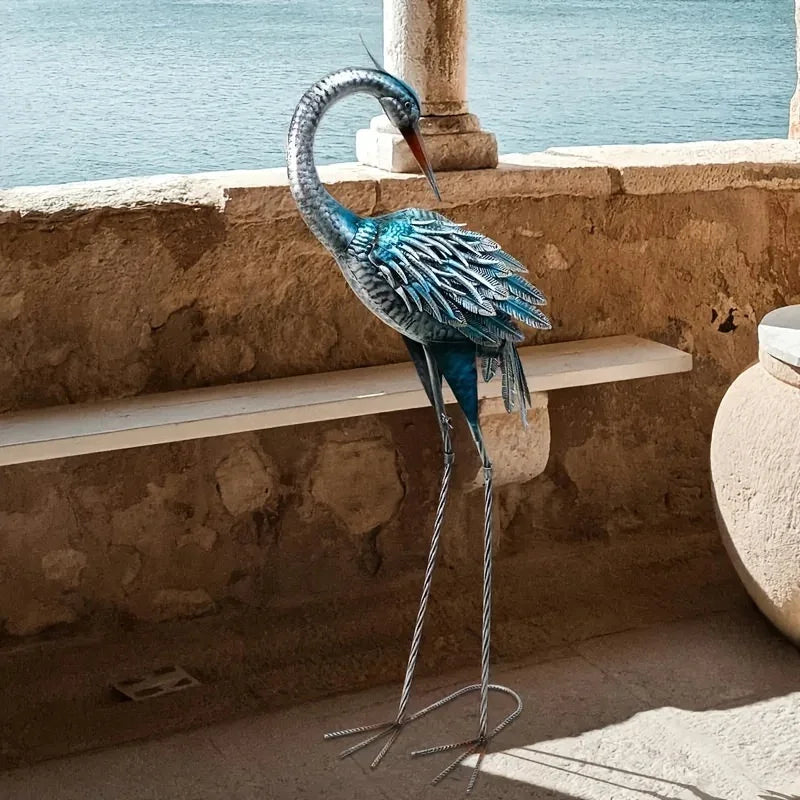 Rustic blue heron outdoor statue with detailed metallic feathers standing on a stone patio.
