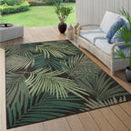 Tropical palm leaf pattern outdoor rug in black and green on a wooden patio deck