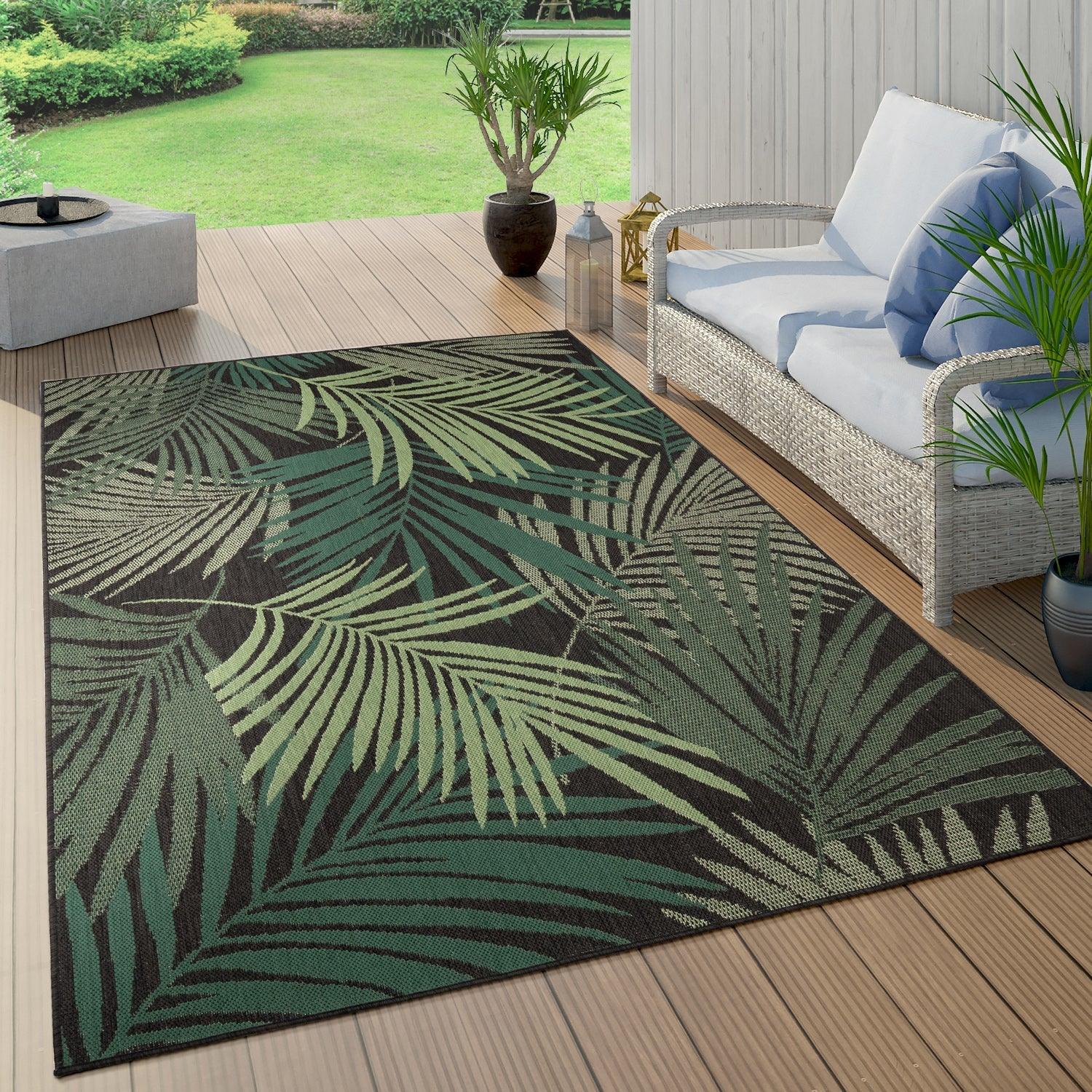 Tropical palm leaf pattern outdoor rug in black and green on a wooden patio deck