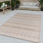 Modern cream beige flatweave outdoor rug with boho patterns on a patio with a wooden sofa and plants.