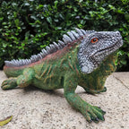 Realistic iguana garden statue with detailed green scales and orange eyes for indoor or outdoor lizard decor.