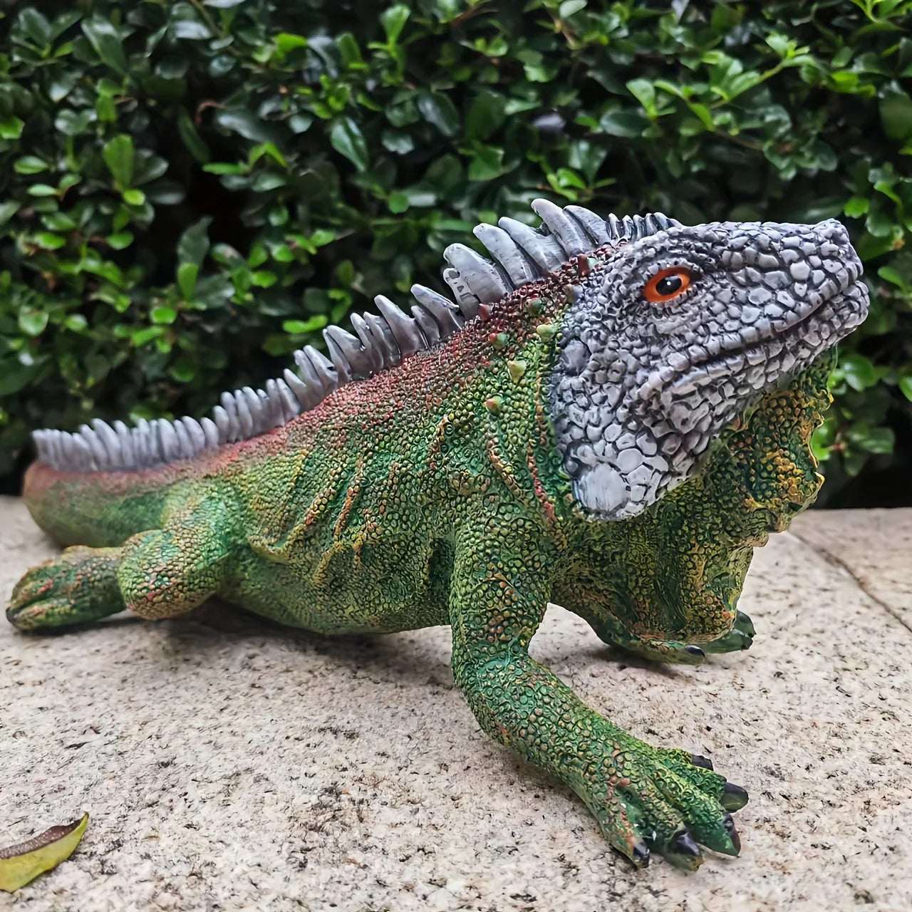 Realistic iguana garden statue with detailed green scales and orange eyes for indoor or outdoor lizard decor.