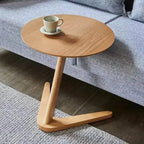 Light wood finished compact wooden coffee table with oval top and minimalist v shaped base for living room use