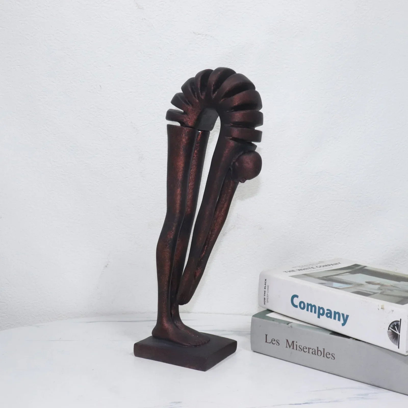 Decorative bronze sculpture on a white surface with books in the background