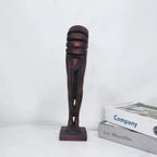 Decorative sculpture of a leg on a white surface with books in the background