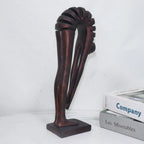 Decorative bronze sculpture on a white surface with books in the background