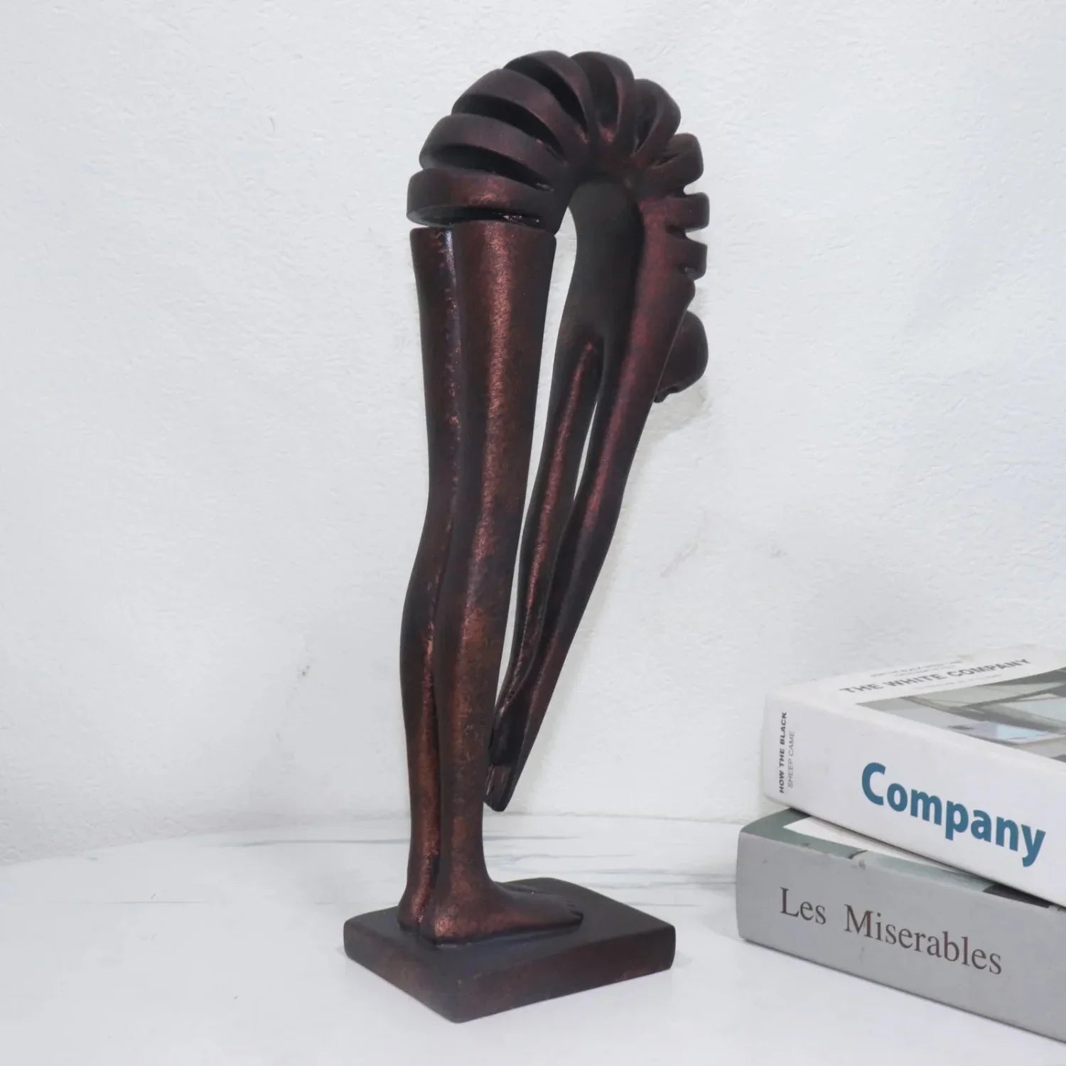 Decorative bronze sculpture on a white surface with books in the background