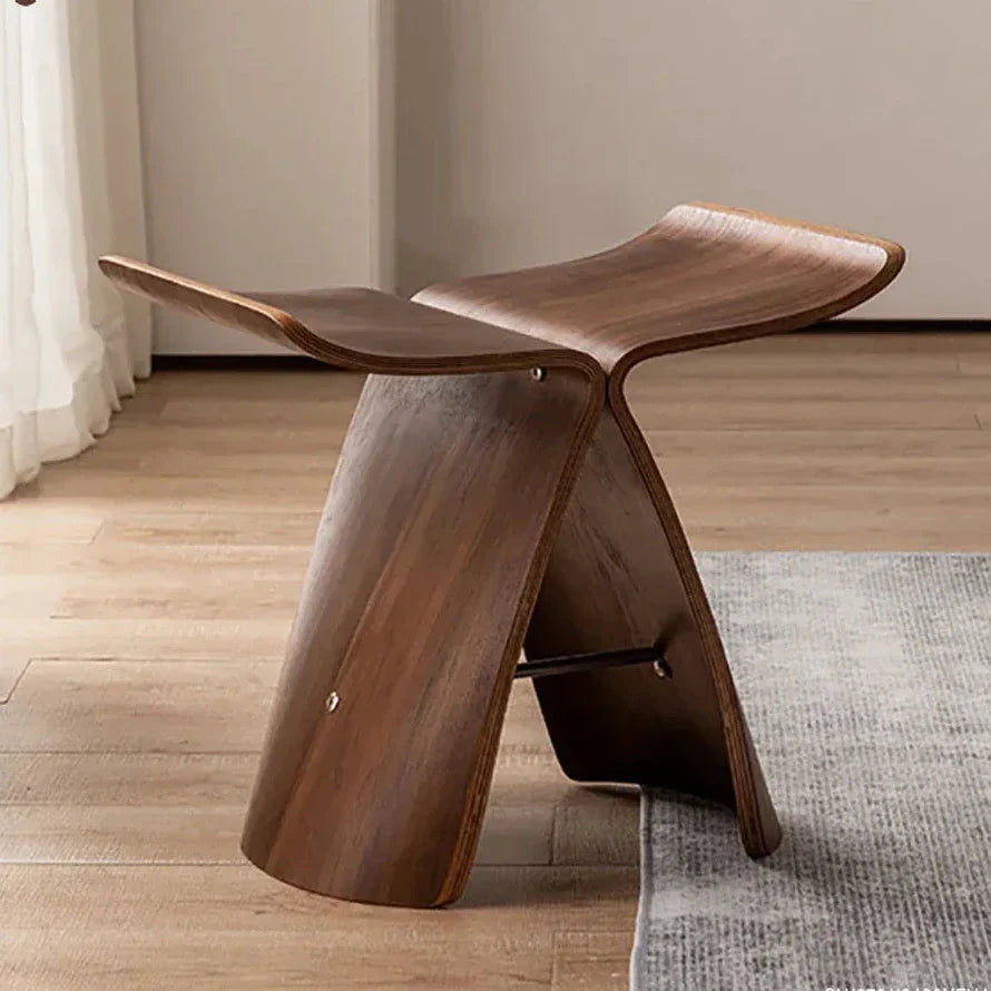 A sleek dark brown solid wood small stool ottoman with modern sculpted design for apartment living spaces