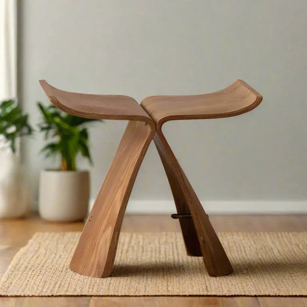 A sleek small stool ottoman made of solid wood with a curved light brown finish for apartment living spaces