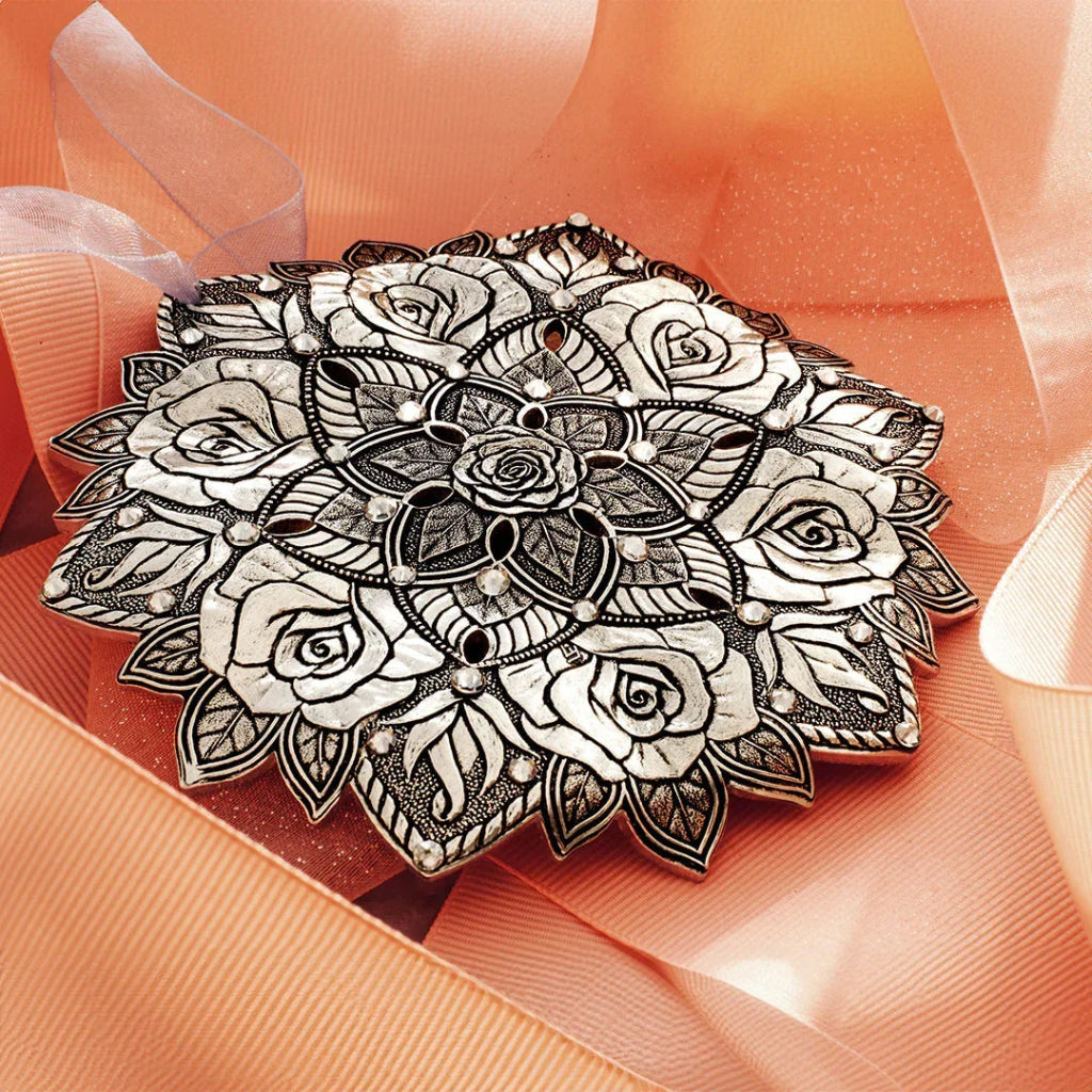 Decorative black and white brooch on a soft peach fabric background