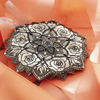 Decorative black and white brooch on a soft peach fabric background