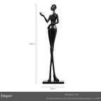 Black frp figurine of a slender woman with raised arm paired with a comforting velvet sofa cushion for living room decor
