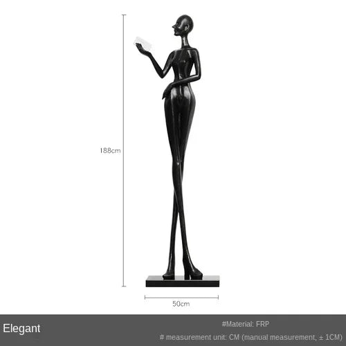 Black frp figurine of a slender woman with raised arm paired with a comforting velvet sofa cushion for living room decor