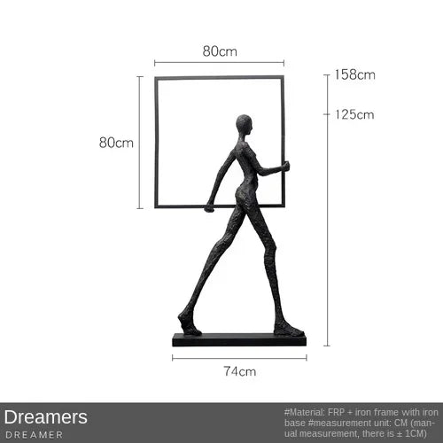 Black metallic figurine holding a square frame displayed next to a comforting velvet large sofa cushion for living room decor
