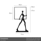 Black metallic figurine holding a square frame displayed next to a comforting velvet large sofa cushion for living room decor