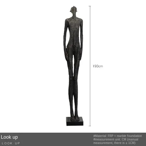 A tall slender black figurine with a textured surface on a matching base complements living room home decor
