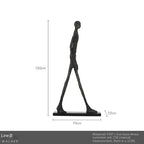 Black abstract human figure sculpture with elongated limbs on iron base complementing living room home decor sofa cushion