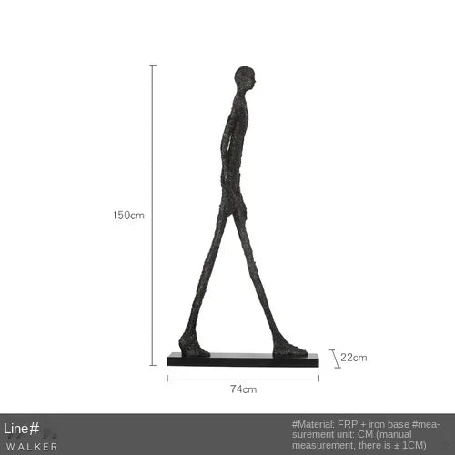 Black abstract human figure sculpture with elongated limbs on iron base complementing living room home decor sofa cushion
