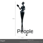 Black frp figurine of a slender woman holding a book paired with a comforting velvet large sofa cushion for living room decor