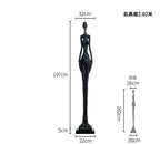 Black slender figurine sculpture with textured surface and elongated form displayed as living room home decor