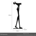Black frp sculpture of stylized human figure with raised arms beside a comforting velvet large sofa cushion for living room decor