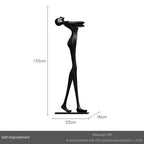 Black frp sculpture of stylized human figure on base displayed next to velvet sofa cushion for living room home decor