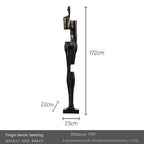 Black abstract figurine sculpture made of frp with angular design standing near sofa cushion for living room decor