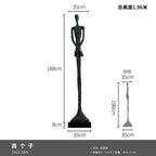Black glass steel sculpture of tall slender figure with elongated limbs as elegant home decor in living room setting