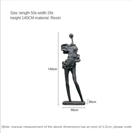 Black resin sculpture of abstract human figure with elongated limbs alongside comforting velvet sofa cushion for living room decor