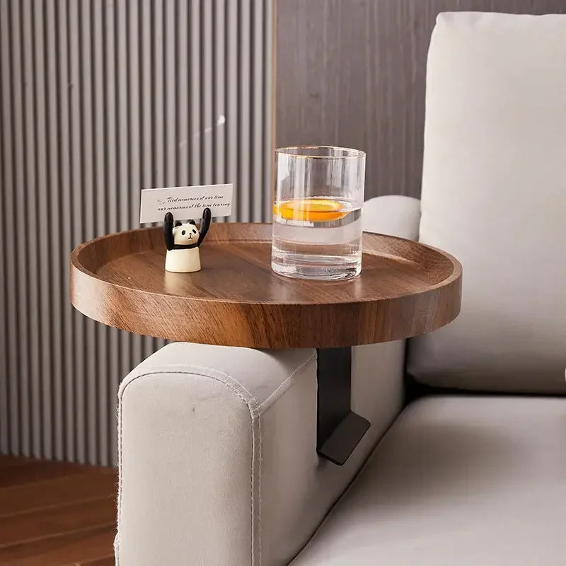 Round wooden sofa tray table with dark brown finish and black metal support attaches to upholstered chair arm