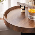 A cream and black panda figurine with raised arms holding a card on a sofa tray table for small spaces