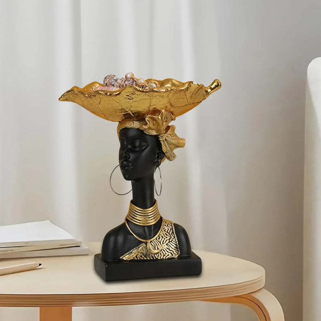 Black resin bust sculpture with gold leaf accents holding a gold decorative wooden storage tray in modern style