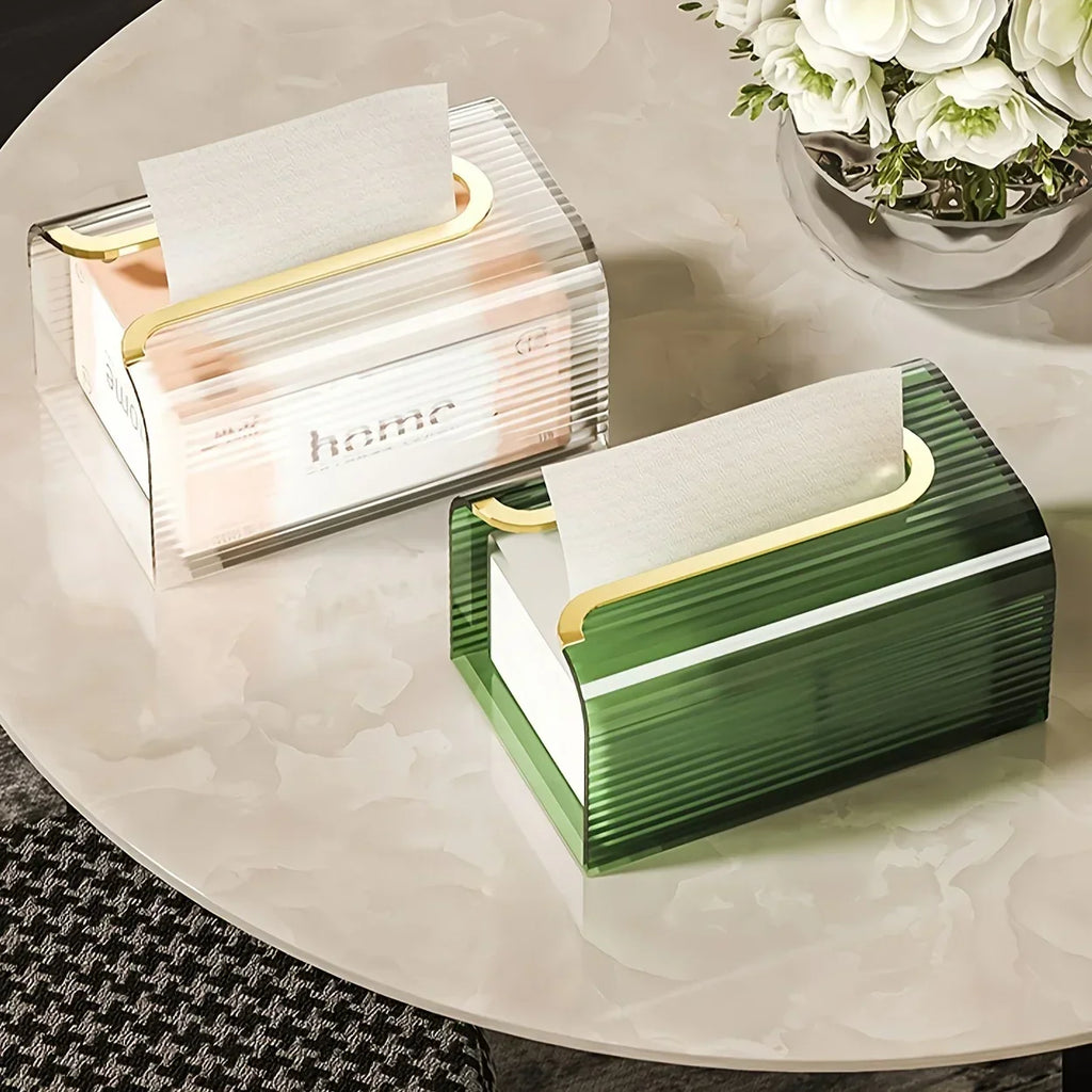 Green and gold tissue box on a marble surface with a white flower arrangement in the background.