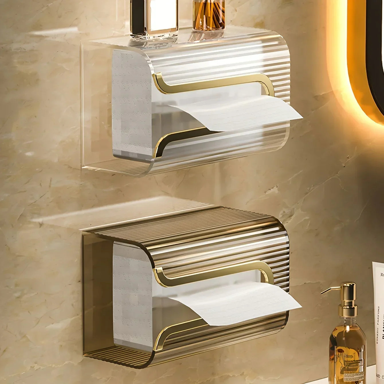 Gold and silver wall-mounted toilet paper holders on a beige tiled bathroom wall.