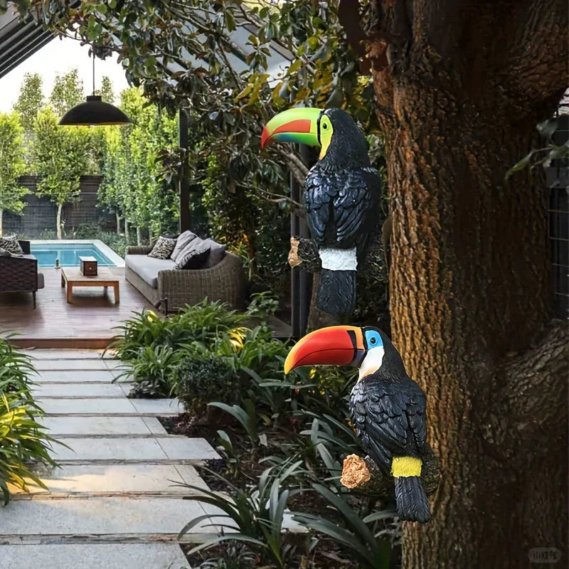 Decorative toucan statues in a garden setting with a pool and patio in the background.