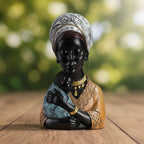 Glossy black resin traditional African mother figurine with white patterned headwrap holding baby in blue fabric