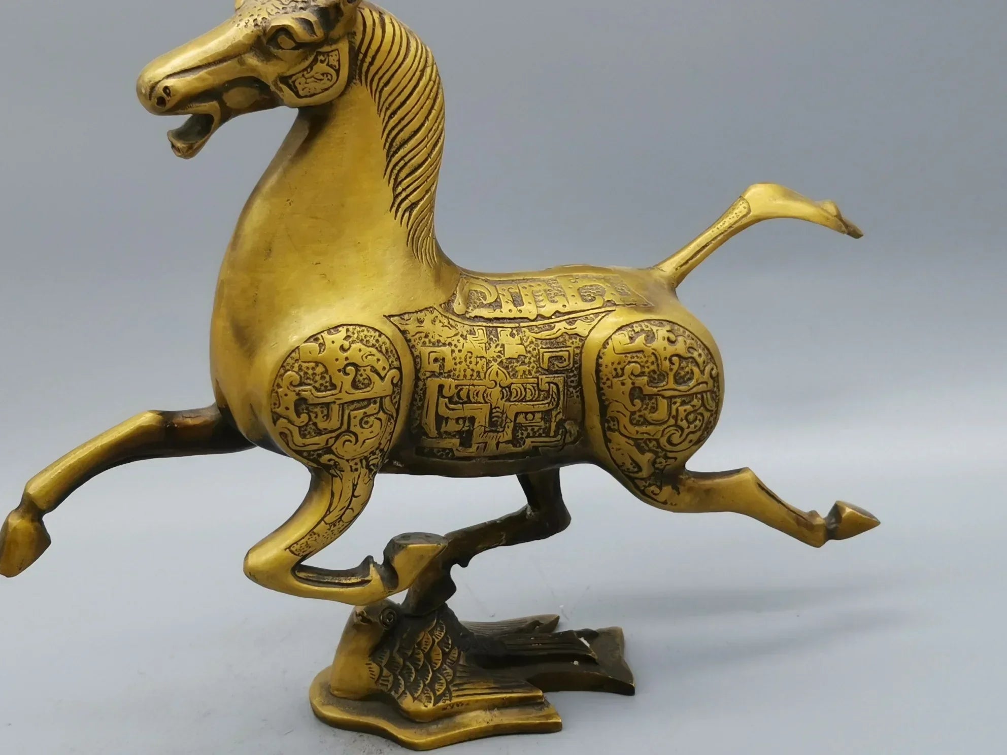 Vintage bronze running horse statue in dynamic rearing pose with intricate engraved patterns for luxury decor