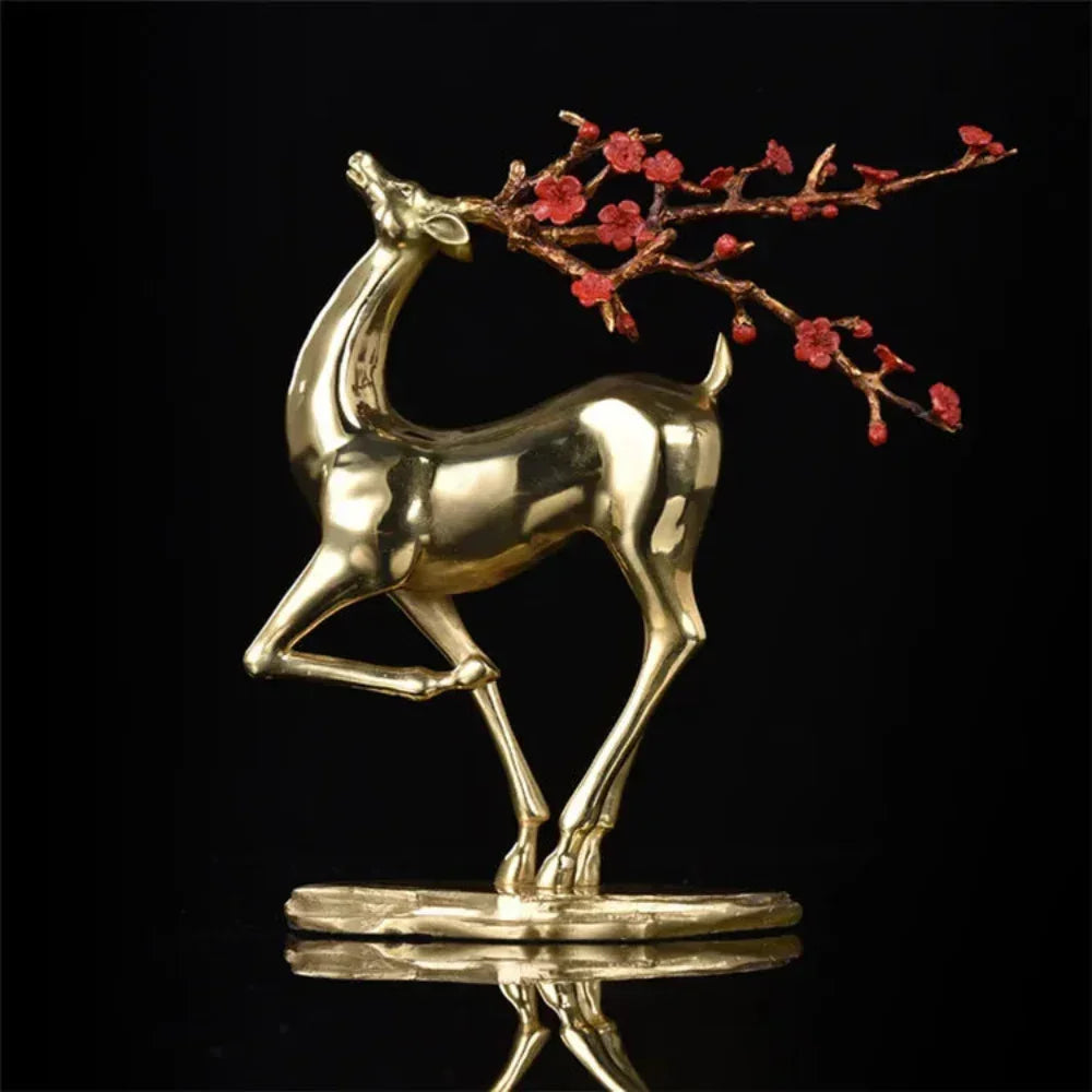 Vintage deer statue in gold with a branch of red blossoms on antlers for elegant home and office decor