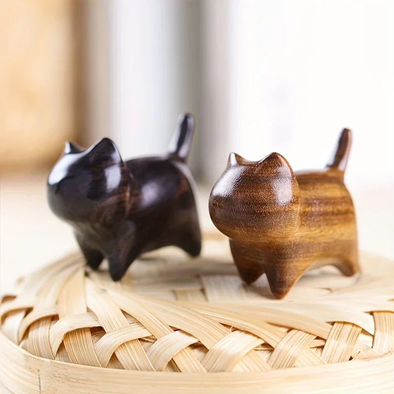 Two wooden cat figurines on a woven surface with a blurred background