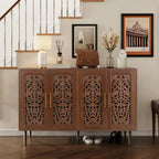 Wooden sideboard with decorative carvings in a room with a staircase and framed pictures.