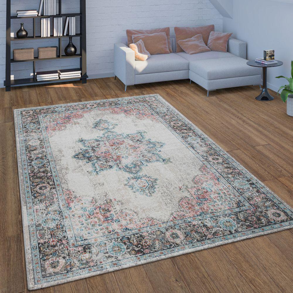 Beige oriental pattern indoor and outdoor rug with distressed accents on a wooden floor in a living room.