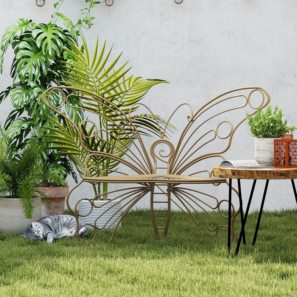 Tan metal garden bench featuring an intricate butterfly-shaped backrest placed on a green lawn.