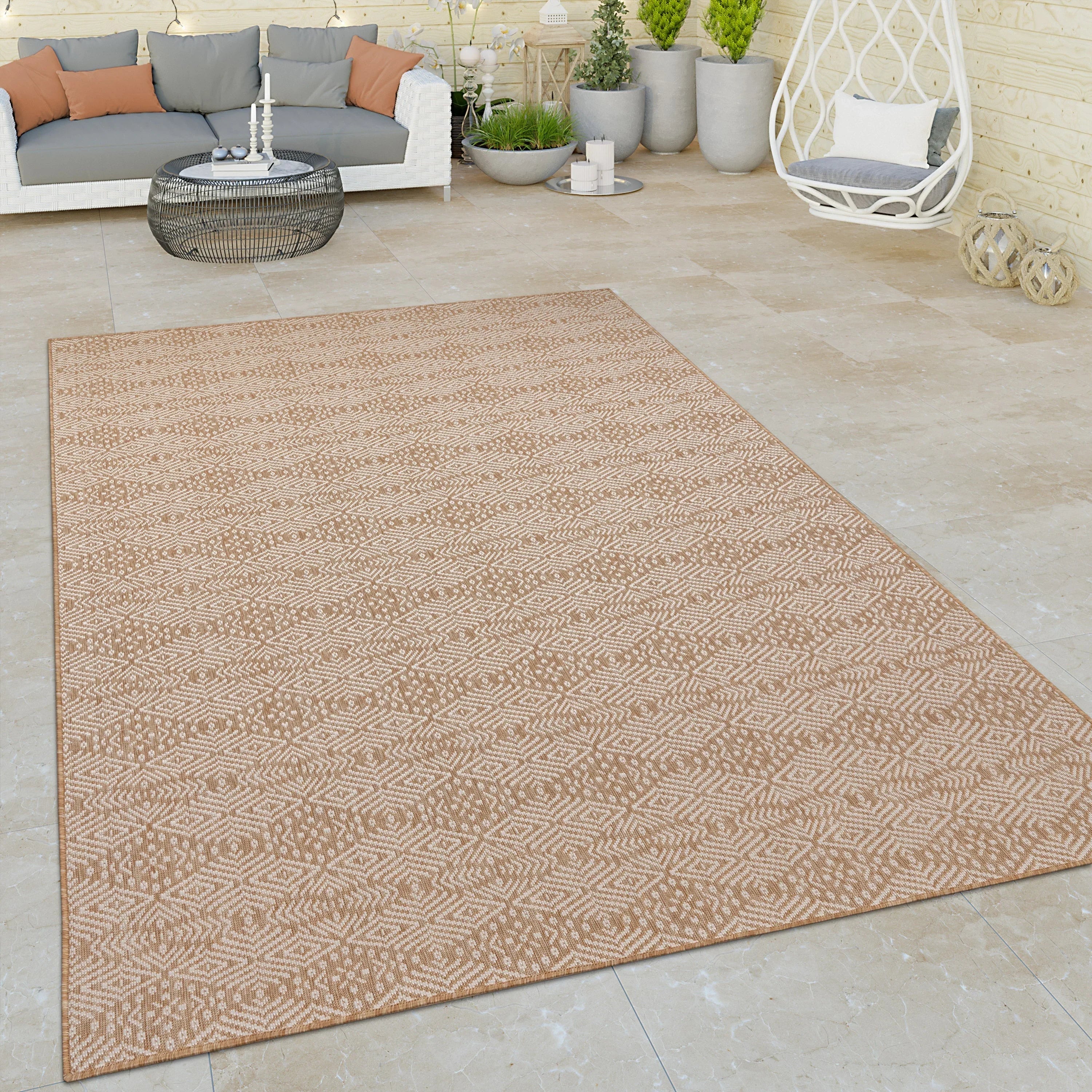 Beige Captera rug with Aztec geometric pattern on a modern outdoor patio.