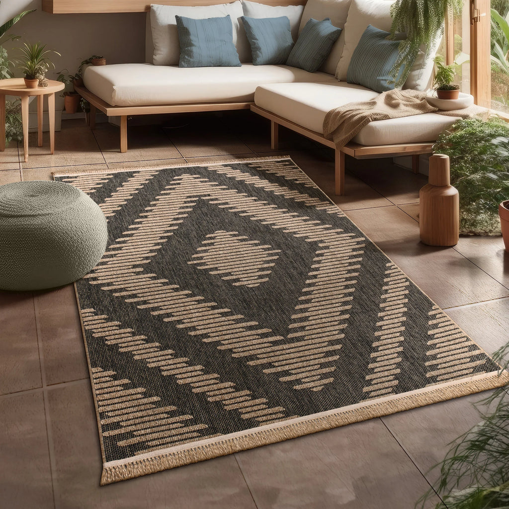 Black and beige bohemian diamond pattern indoor outdoor rug with fringe on a modern patio.