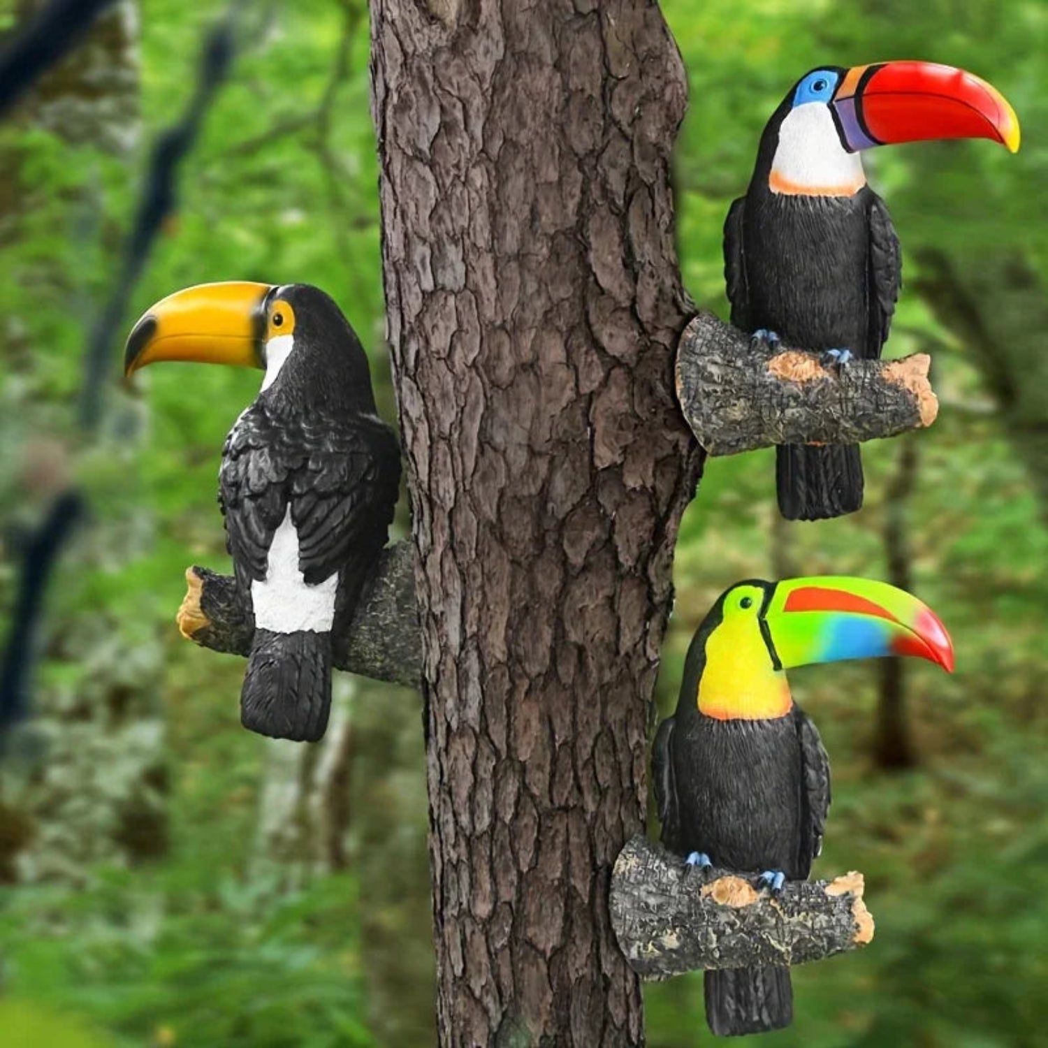 Three colorful ceramic toucan statues with different colored beaks mounted on a tree trunk in a lush garden.