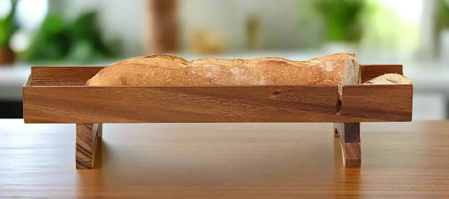 Loaf of bread in a wooden bread holder on a wooden surface with a blurred background