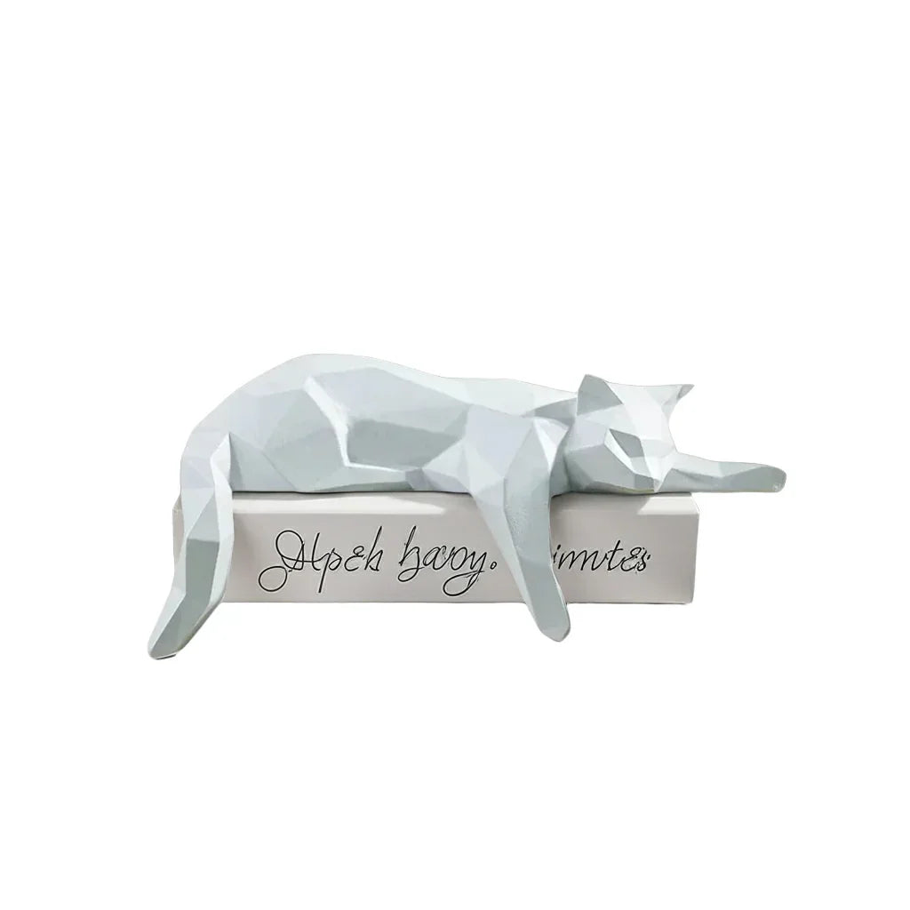 Decorative white cat sculpture on a white surface with keys and a plant in the background.