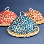 Three handmade bamboo dining covers with colorful geometric woven patterns and white top handles.