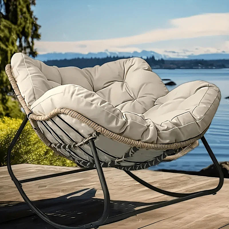 Modern grey weather-resistant outdoor sofa with tufted cushions on a black frame overlooking a scenic lake.
