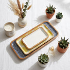 Decorative trays with geometric patterns on a white surface with plants and candles.